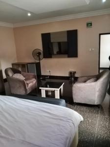 a hotel room with a bed and couches and a television at Clover Apartments and suites in Abuja