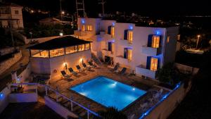 a large white house with a swimming pool at night at Blue Dolphin Aegina in Vaia