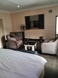 a hotel room with a bed and chairs and a tv at Clover Apartments and suites in Abuja +50 photos