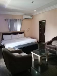 a hotel room with a bed and a couch and chairs at Clover Apartments and suites in Abuja