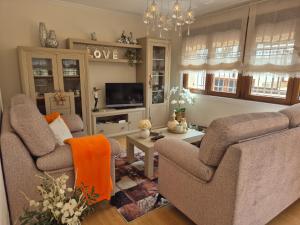 a living room with two couches and a tv at Casa da Xoiña in Foz