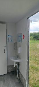 a bathroom with a sink and a field at Domek GLAMPING na Polu namiotowym RADOŚĆ in Okuninka