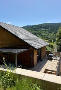 a house with a deck with a table and chairs at Chalet Iris, spa privatif, 4p in Rochesson