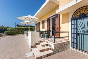 a house with a patio with a table and an umbrella at House&Villas - Residence Miramare in Avola