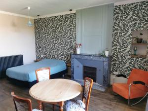 a room with a table and a bed and a fireplace at Fleurs et Abeilles in Faye-lʼAbbesse