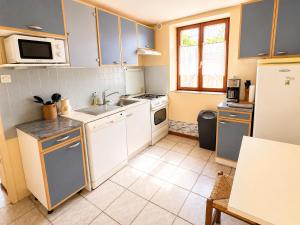 a kitchen with white cabinets and a sink and a refrigerator at Le petit Chai in Chémery +5 photos