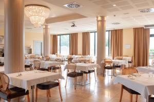 a restaurant with white tables and chairs and windows at Grand Hotel Forlì in Forlì