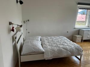 a white bedroom with a bed and a window at Byt Staré Mesto in Liptovský Mikuláš +4 photos