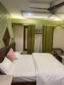 a bedroom with a white bed with a ceiling fan at Vakil Villa in Srinagar