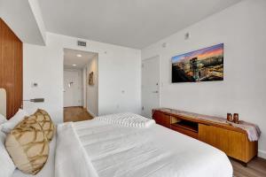 a white bedroom with a bed and a desk at Ocean & Canal View Studio Beach 8 Min Pool 1906 in Hallandale Beach