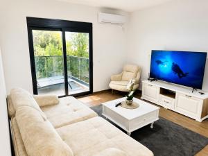a living room with a couch and a flat screen tv at Swiss Luxury Appartement in Dobra Voda