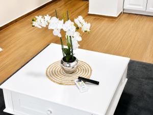a vase with white flowers on a table at Swiss Luxury Appartement in Dobra Voda