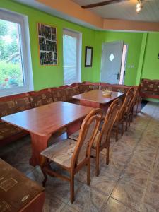 a restaurant with wooden tables and chairs and green walls at Privát Čujová in Hrabušice
