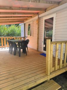 a screened porch with a table on a deck at Camping les sablons in Vergeroux