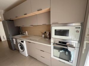 a kitchen with a microwave and a washer and dryer at Appartement avec piscine chauffée et Tennis proche Deauville in Touques
