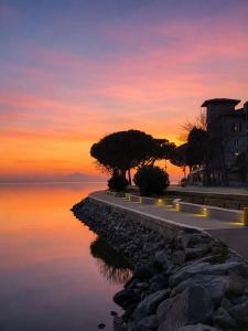 a sunset over the water with trees and a building at La Perla in Passignano sul Trasimeno