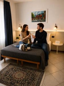 a man and woman sitting on a bed drinking wine at Le Camere DI Lucia Affittacamere in Colà di Lazise +15 photos