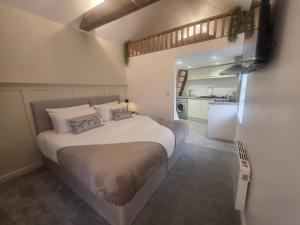a bedroom with a large bed and a kitchen at The Loft Studio Westbury in Westbury