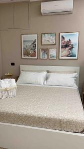 a bedroom with a white bed with pictures on the wall at Carla's studio in Pompei