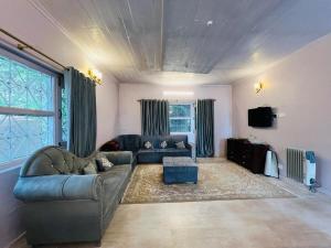 a living room with a couch and a tv at Haven Daisy Meadows - 2BR Cottage with Lawn in Changla Gali in Chhāngla Gali