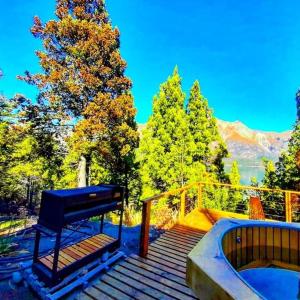 a bench sitting on a wooden deck with a bath tub at Cabaña sobre el Lago Cholila in Cholila