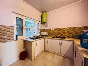 a kitchen with white cabinets and a sink and a window at Haven Daisy Meadows - 2BR Cottage with Lawn in Changla Gali in Chhāngla Gali