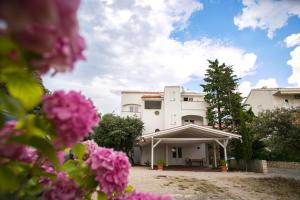un edificio blanco con flores rosas en primer plano en Apartments Ostrea - Mimoza, en Novalja
