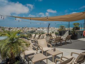 a patio with chairs and tables and a view of a city at Aparthotel Adagio Malta Central in Msida