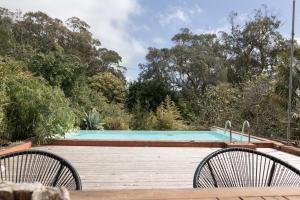 two chairs sitting on a wooden deck near a swimming pool at Casa Do Populo in Ponta Delgada