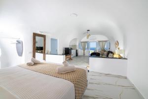 a white room with a bed and a mirror at Sun Angelos Oia - Luxury Cave Suites in Oia +286 photos