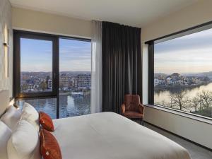 a hotel room with a large bed and large windows at Mercure Namur Hotel in Namur