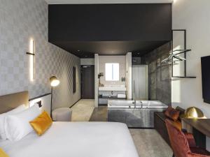 a bedroom with a bed and a bathroom with a tub at Mercure Namur Hotel in Namur