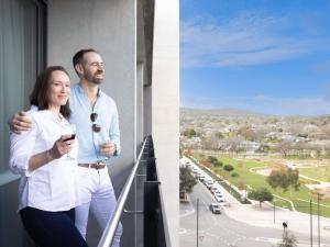 a man and a woman standing on a balcony with a glass of wine at The Sebel Canberra Campbell in Canberra +49 photos