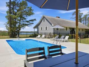 a swimming pool with chairs and a house at Oyster Haven in Cambridge