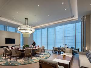 a hotel lobby with tables and chairs and a person in the background at Pullman Huai'an in Huai'an
