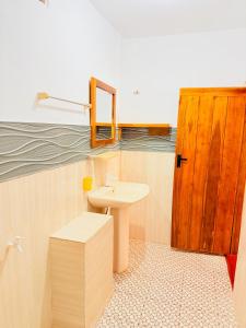 a bathroom with a sink and a wooden door at Beach Cab Resort in Arugam Bay