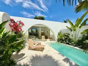 a villa with a swimming pool and two lounge chairs at Dolce Suites in Uluwatu