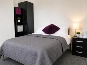 a bedroom with a bed with a purple pillow on it at Cinderhouse Highbury Vale in Nottingham