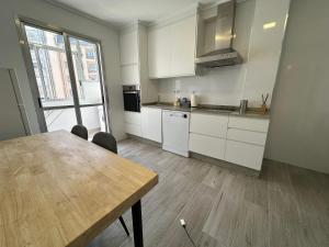 a kitchen with white cabinets and a wooden table at Candle Home Sáenz Díez in Ourense +21 photos