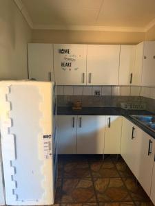 a kitchen with white cabinets and a refrigerator at Root&Roam Nature in Malelane
