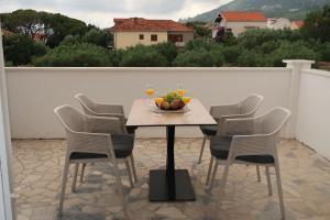 a table with chairs and a bowl of fruit on a patio at Dalmatinac Residence in Orebić