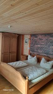 a large wooden bed in a room with a brick wall at Ferienzentrum Briesensee in Neu Zauche