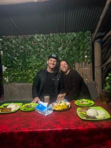 a man and woman sitting at a table with food at Above the Clouds Camp in Kintamani