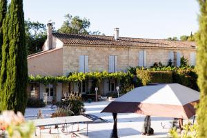 a table with an umbrella in front of a building at Château Catherine de Montgolfier - B&B et Gites - Piscine - Domaine viticole bio avec dégustation in Narbonne