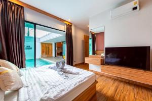 a bedroom with a large television and a bed with towels at King Arthur Pool Villa in Nong Prue +62 photos