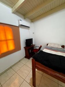 a bedroom with a bed and a desk and a tv at Raíces Vivas Dúplex - Cochera Privada en Oberá in Oberá