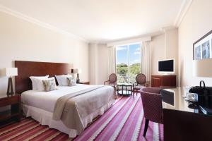 a hotel room with a large bed and a television at Hôtel Juana in Juan-les-Pins
