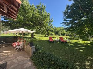 a patio with tables and chairs and an umbrella at Le petit gîte in Saint-Étienne-le-Laus