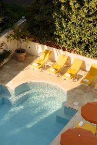 a group of yellow chairs and a swimming pool at Hôtel Juana in Juan-les-Pins