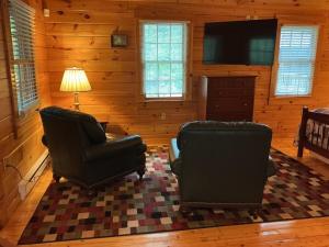 a living room with two chairs and a television at Rivers Edge Cabins - Deer Run in Cushing
